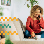 Woman sitting at home and laughing while talking on the phone