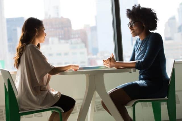 Zwei Frauen sitzen am Tisch und unterhalten sich