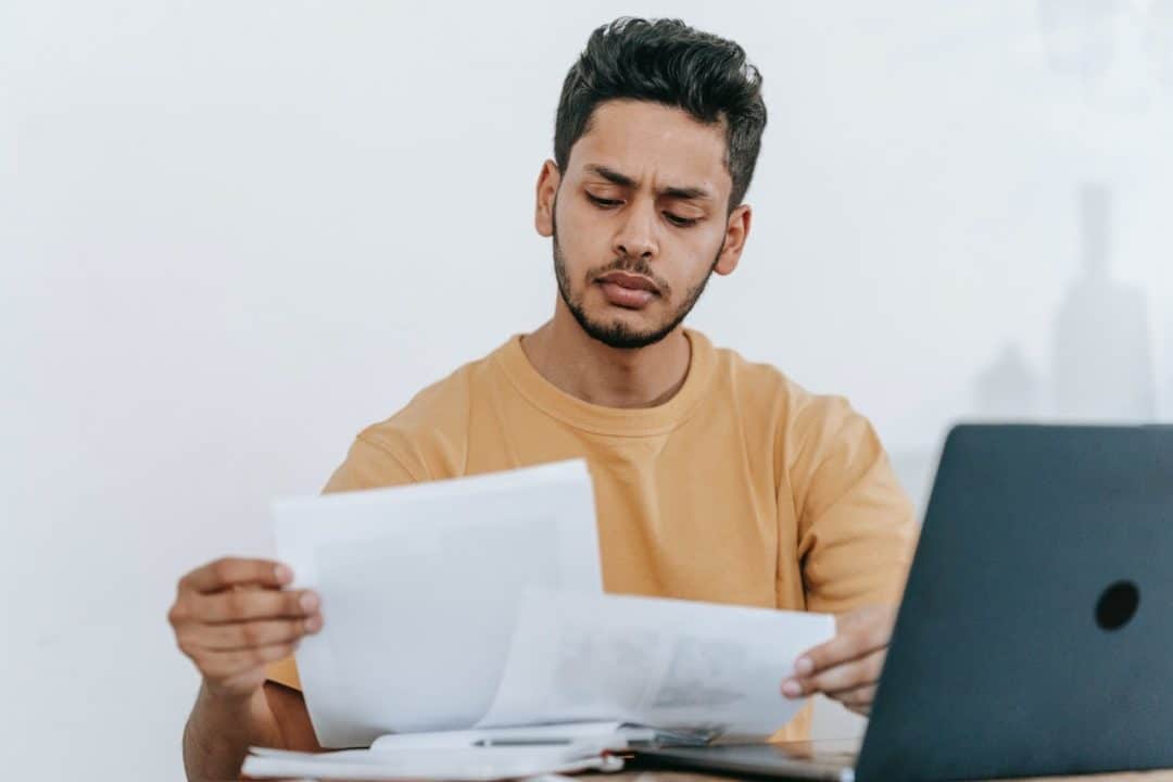 Man reading papers in front of the laptop