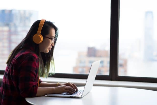 woman using a laptop while wearing headphones