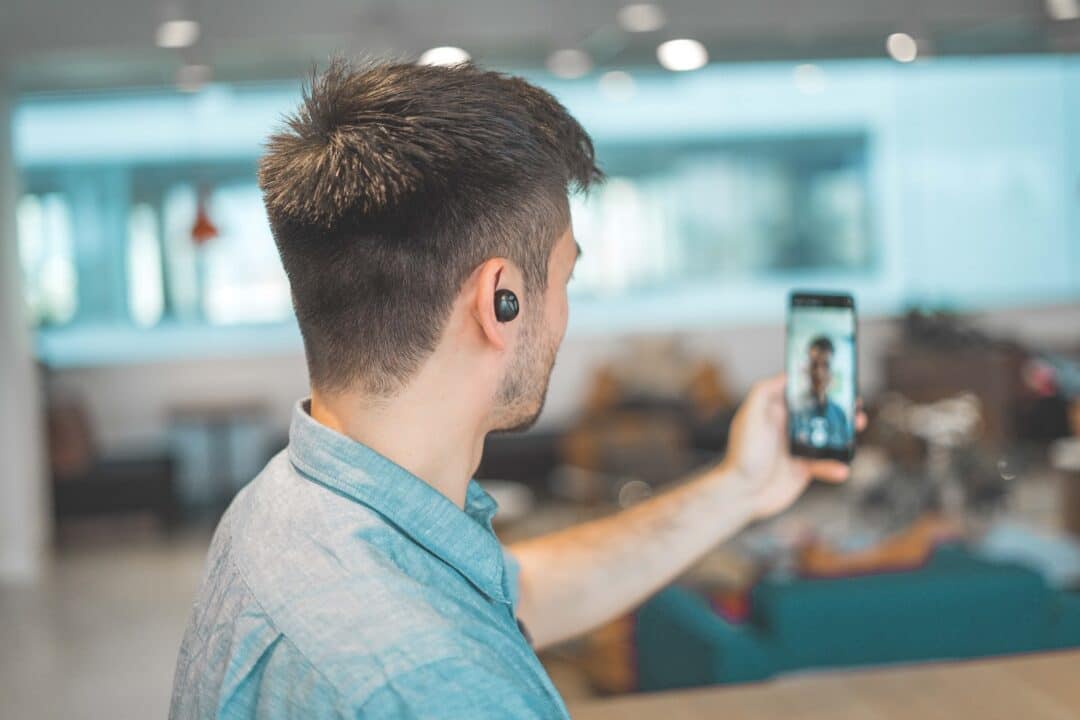 shallow focus photo of man in gray collared top taking an Instragram reel