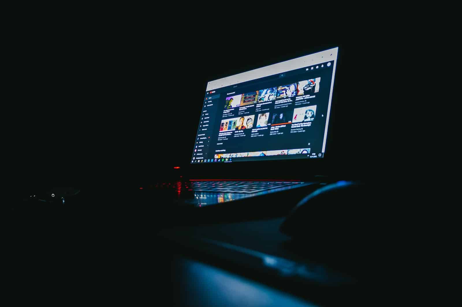 how to write closed captions for youtube: a laptop screen in a dark room displaying the homepage of YouTube