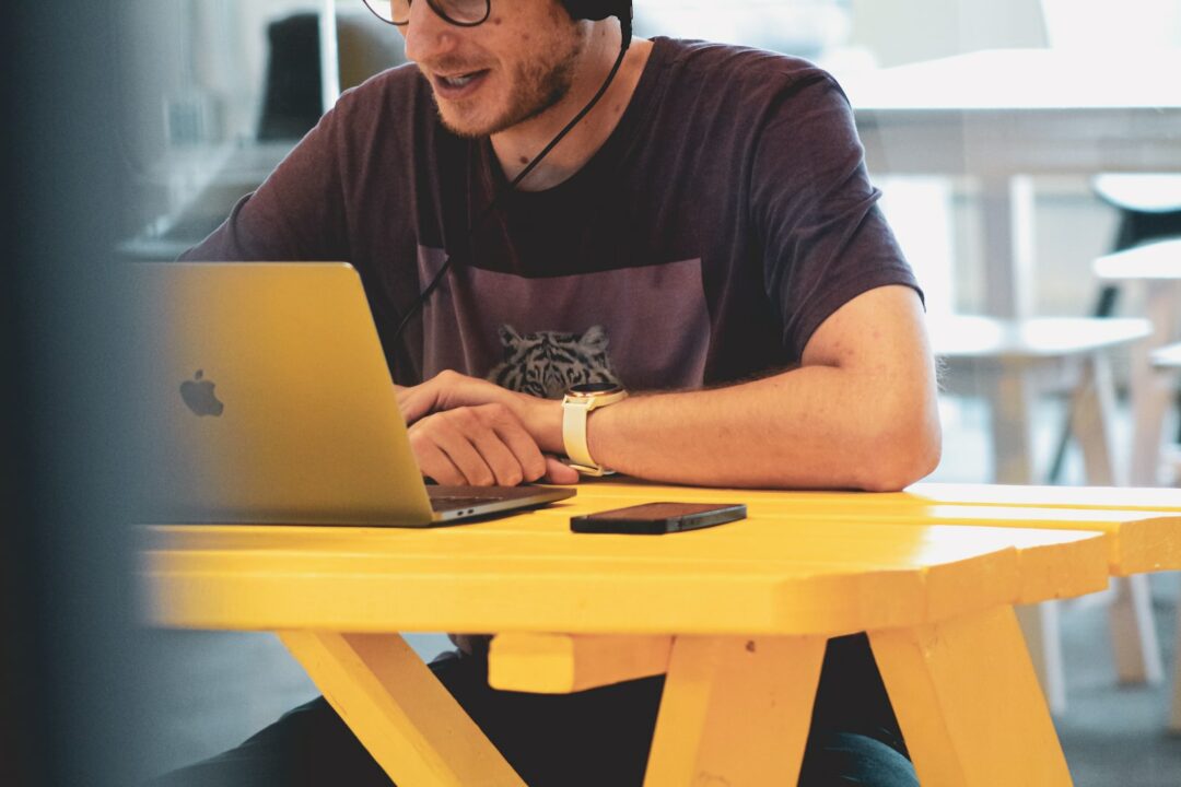 Student sitzt mit Laptop am Tisch an einer Vorlesung