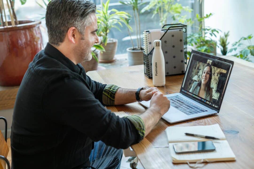 Mann in schwarzem Pullover mit Macbook Pro