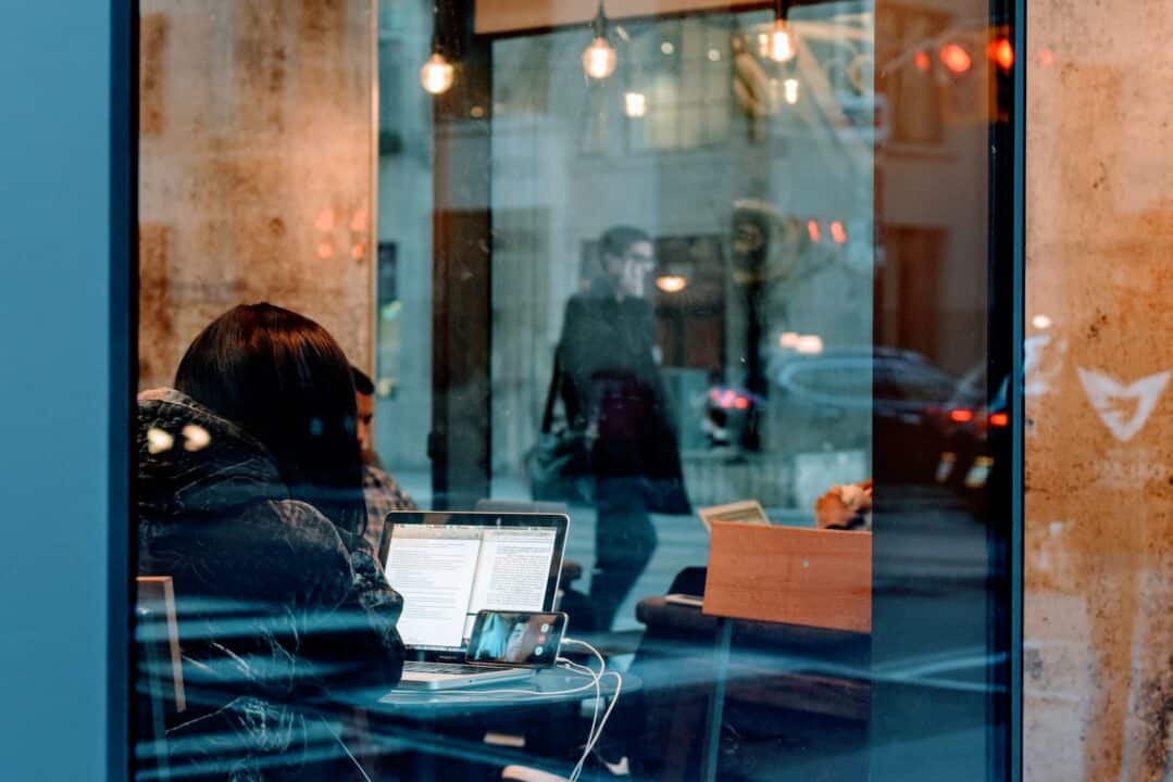 Frau in einem Gebäude sieht ein Video mit Untertiteln auf ihrem Laptop